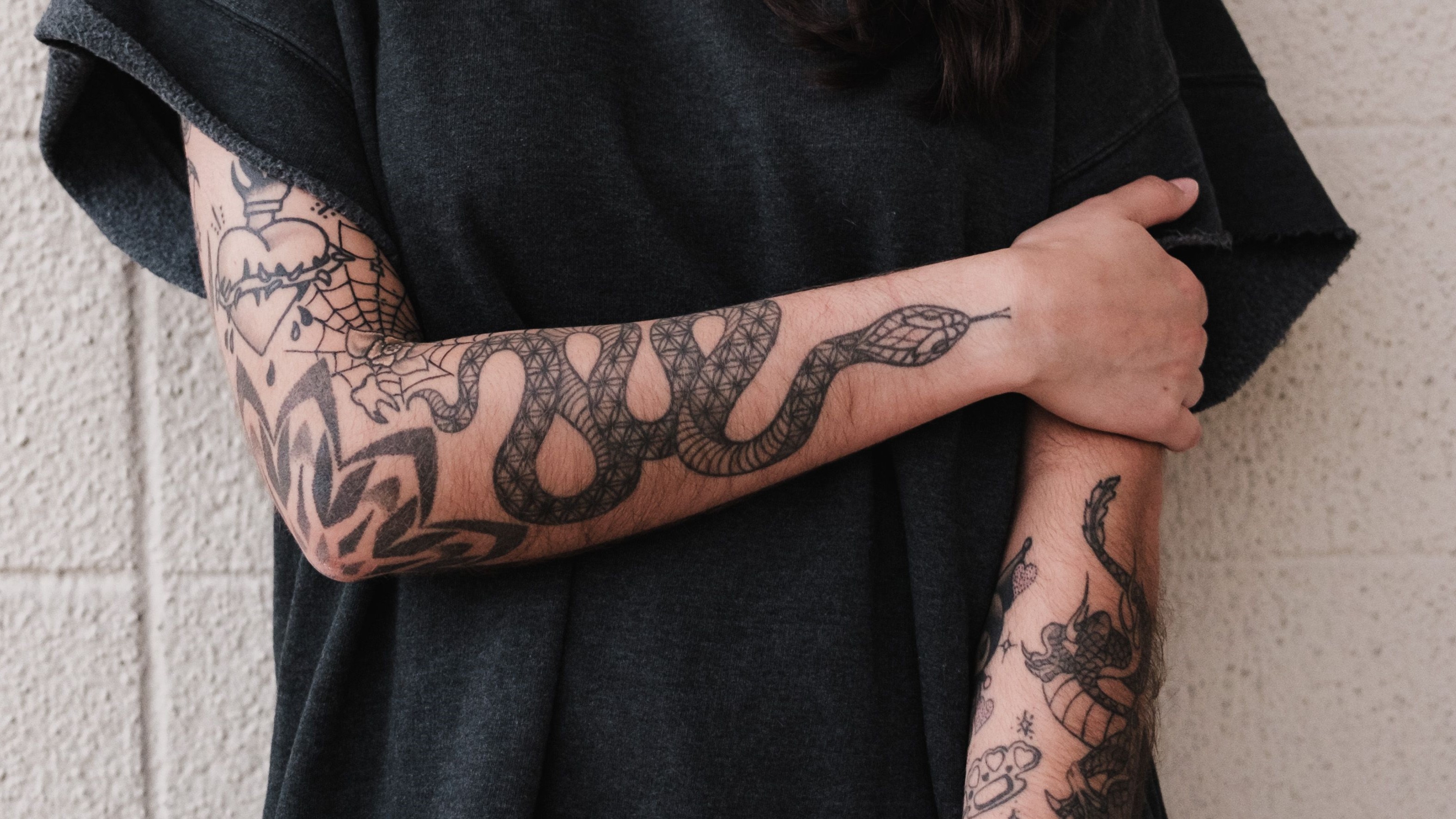 Tatuagem de cobra enrolada no braço em preto e cinza